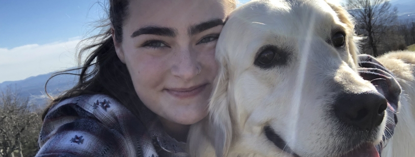 Girl hugging white golden retriever outside