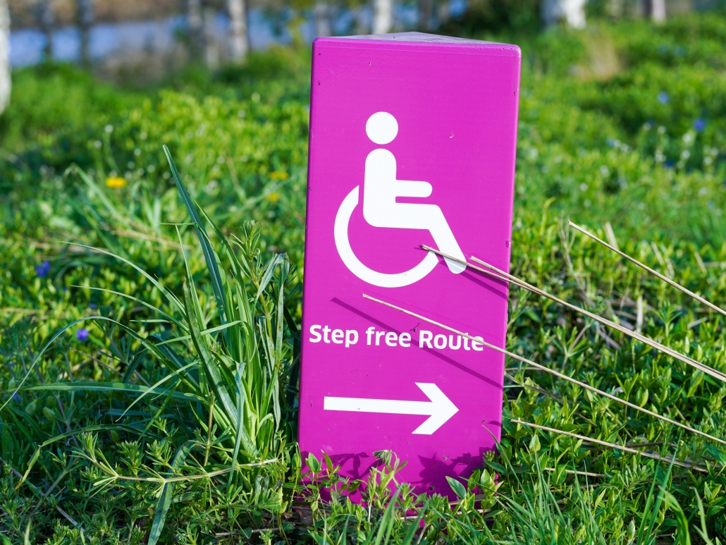 Pink handicap sign that reads "step free route" sitting in the grass